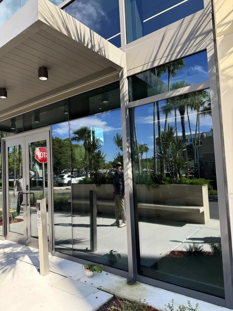 Underside of the main entrance canopy showing metal roof panels and lighting above glass doors.