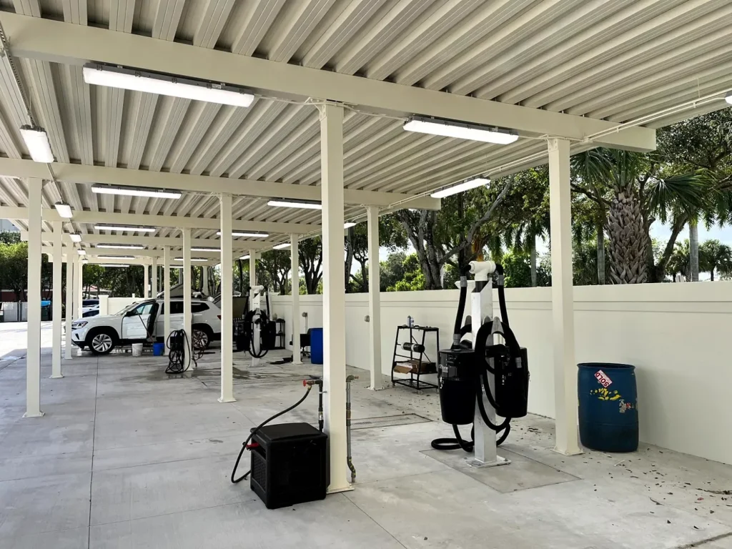 Angled view along the detailing bays showing the aluminum roof panels, white support columns and overhead lighting.